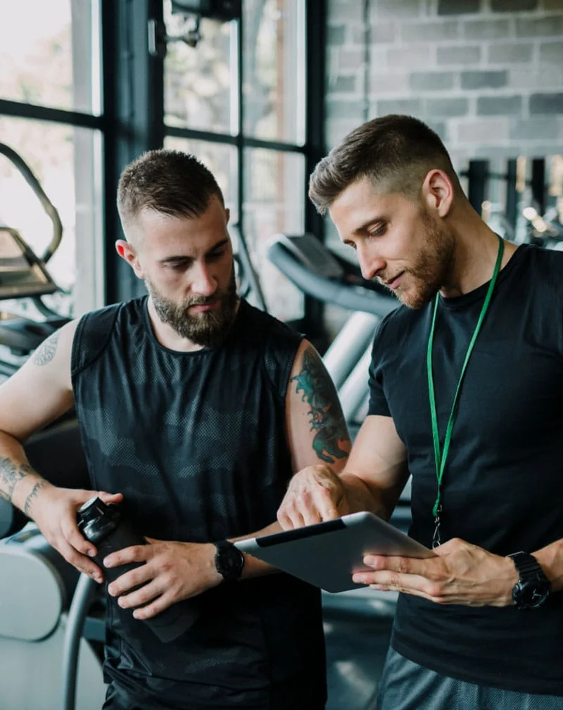 Entrenador personal asesorando a un cliente durante un entrenamiento en el gimnasio